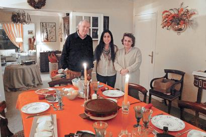 A student with their host parents standing at a set dining room table in a Paris homestay.