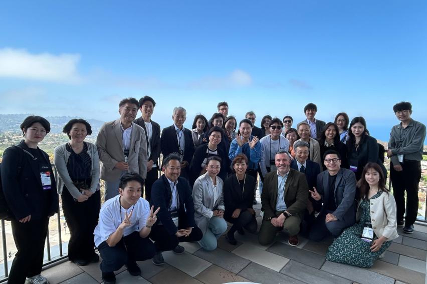 A group of SAF and Asian university reps pose on a balcony overlooking UC San Diego campus.