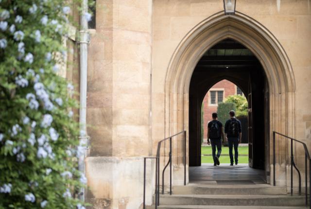 two students walking under large building with pointed arch