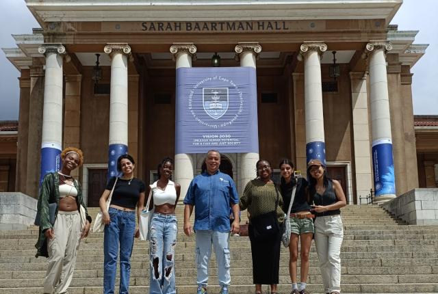 Students stand and smile in front of the University of Cape Town
